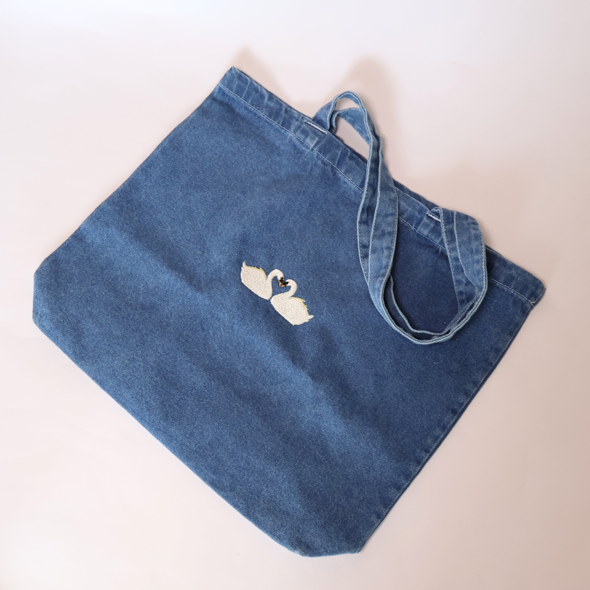 embroidered swans on denim tote bag displayed on white background