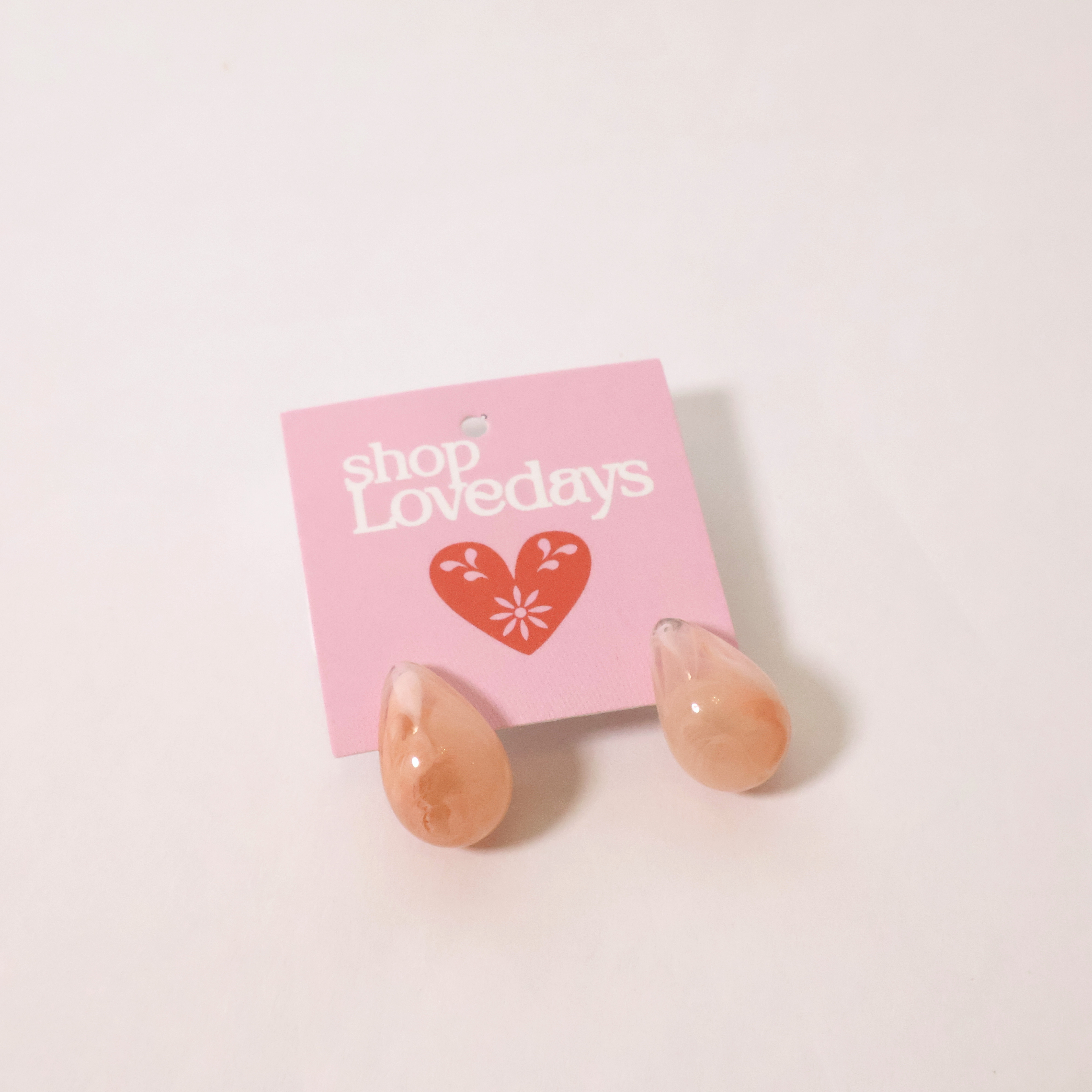 peachy pink teardrop earrings on a product tag shown on a white backdrop
