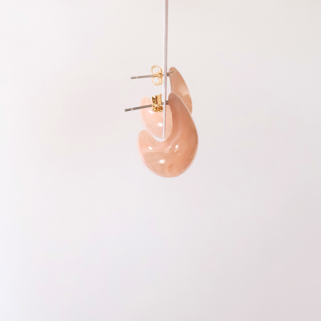 Side view of peachy pink teardrop shaped earrings to show shape on a white backdrop