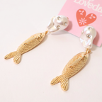 angled view of faux pearl, crystal, and metal fish earrings on a product card displayed on a white background