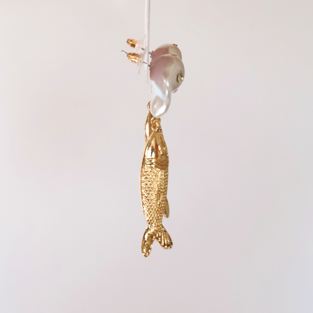 side view faux pearl, crystal, and metal fish earrings on a product card displayed on a white background