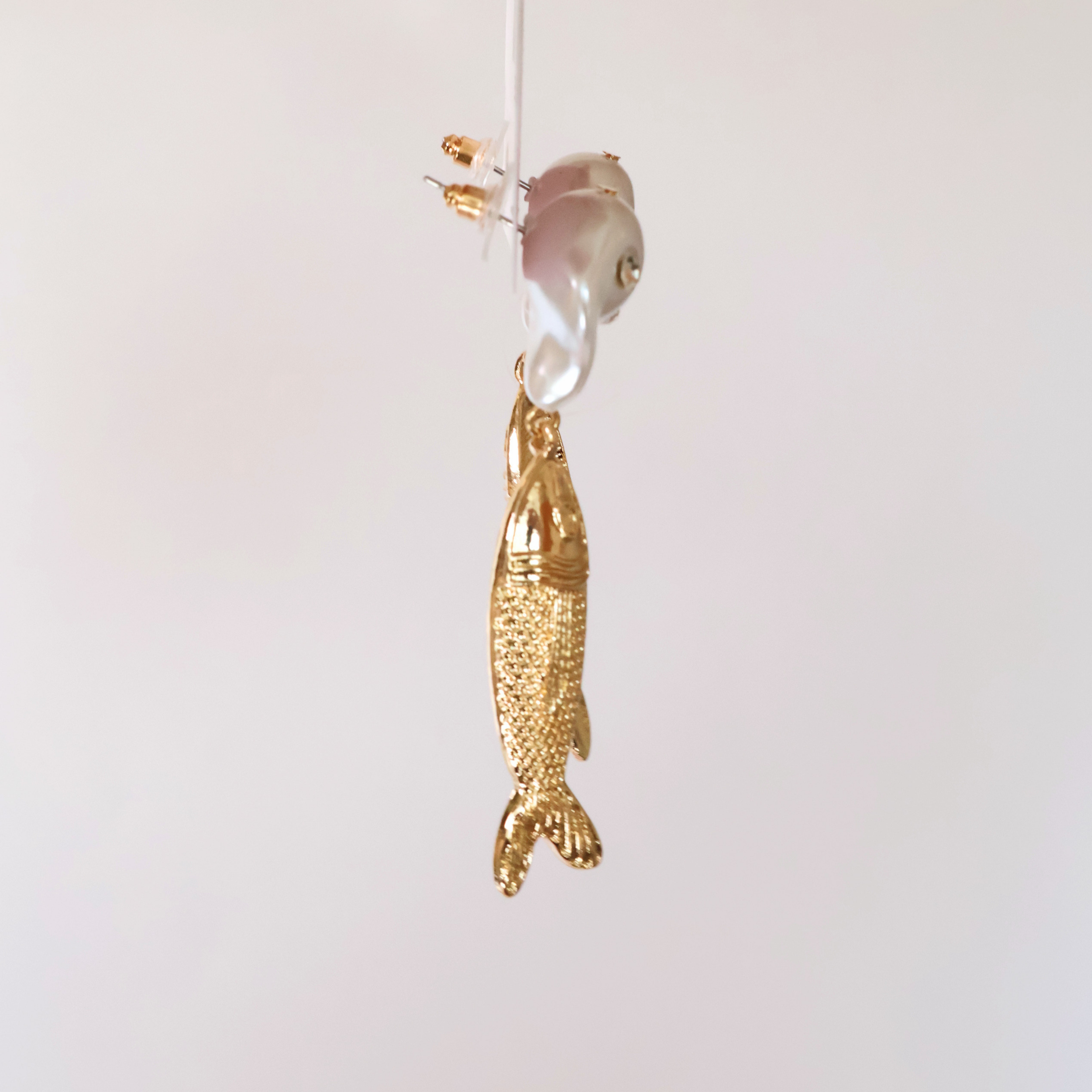 side view faux pearl, crystal, and metal fish earrings on a product card displayed on a white background
