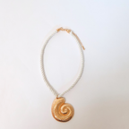cream rope and brassy metal necklace with metal shell pendant displayed on a white background