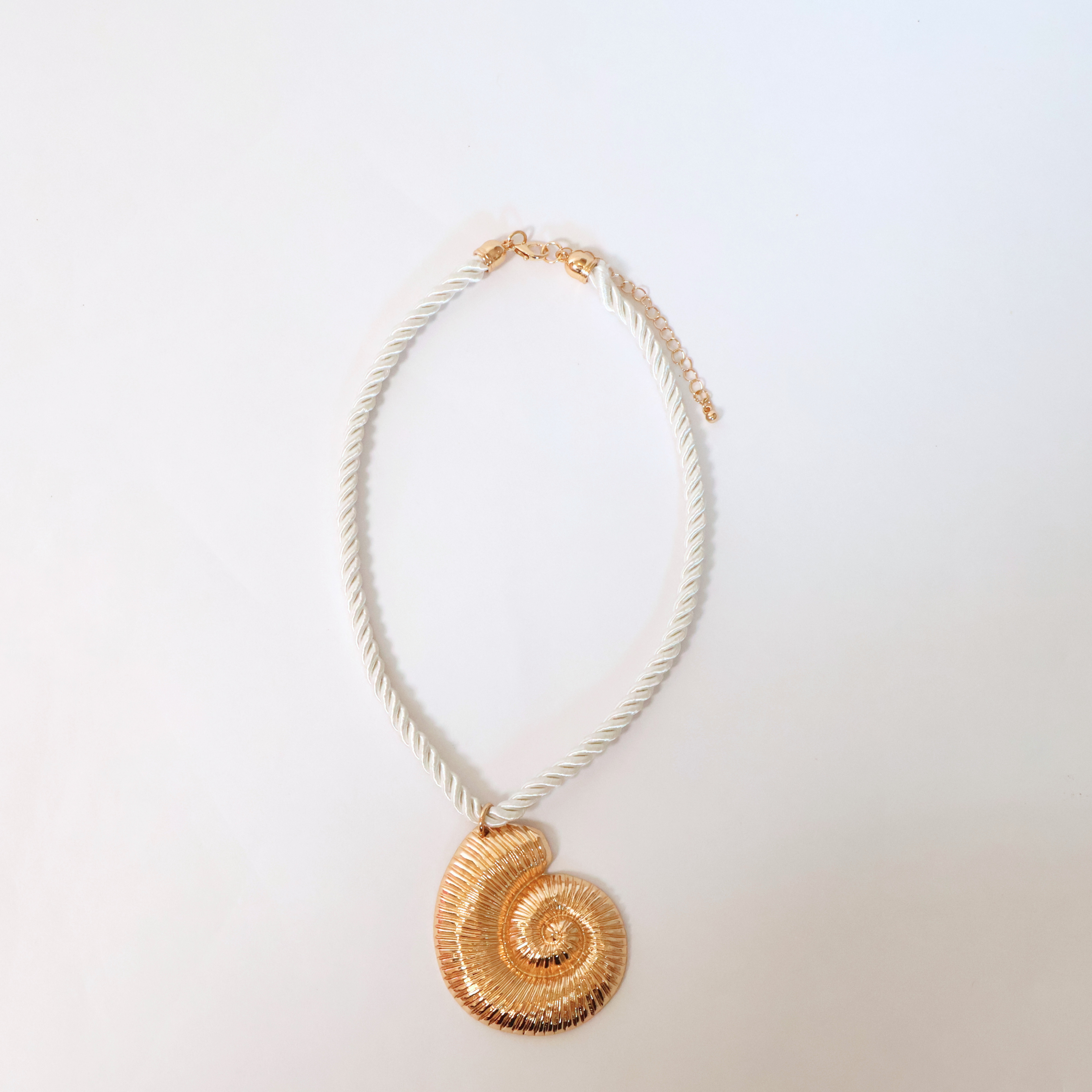 cream rope and brassy metal necklace with metal shell pendant displayed on a white background