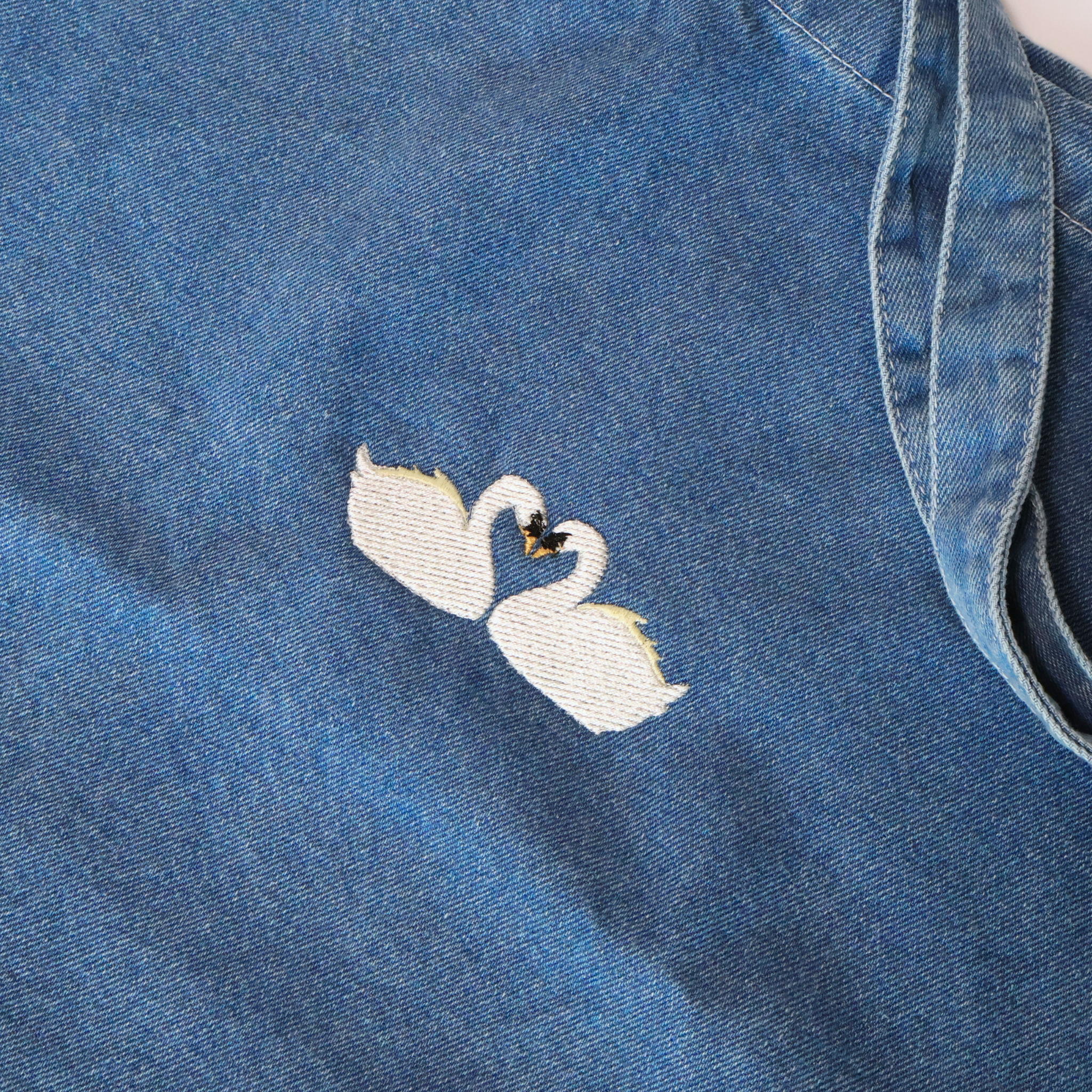 close up photo of embroidered swans on tote bag