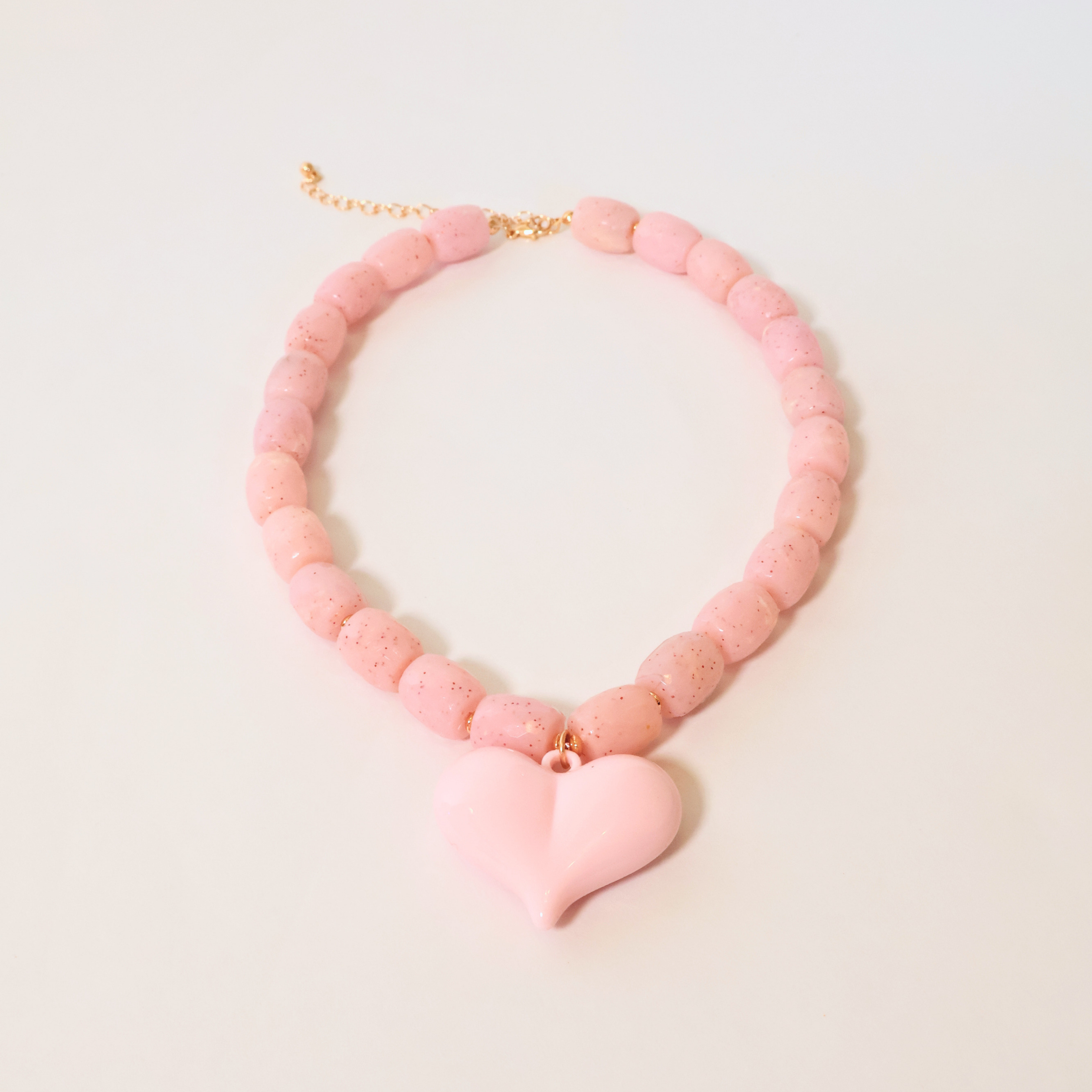 Pink beaded necklace with a heart pendant on a white background