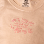 Close up photo of the Tilly Tee showing the embroidered sewing icons and "hot girls have grandma hobbies" wording