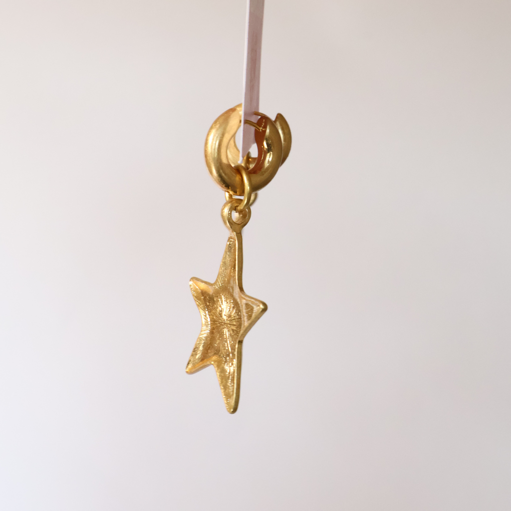 side view of star pendant earrings on gold hoop on a product card displayed on a white background