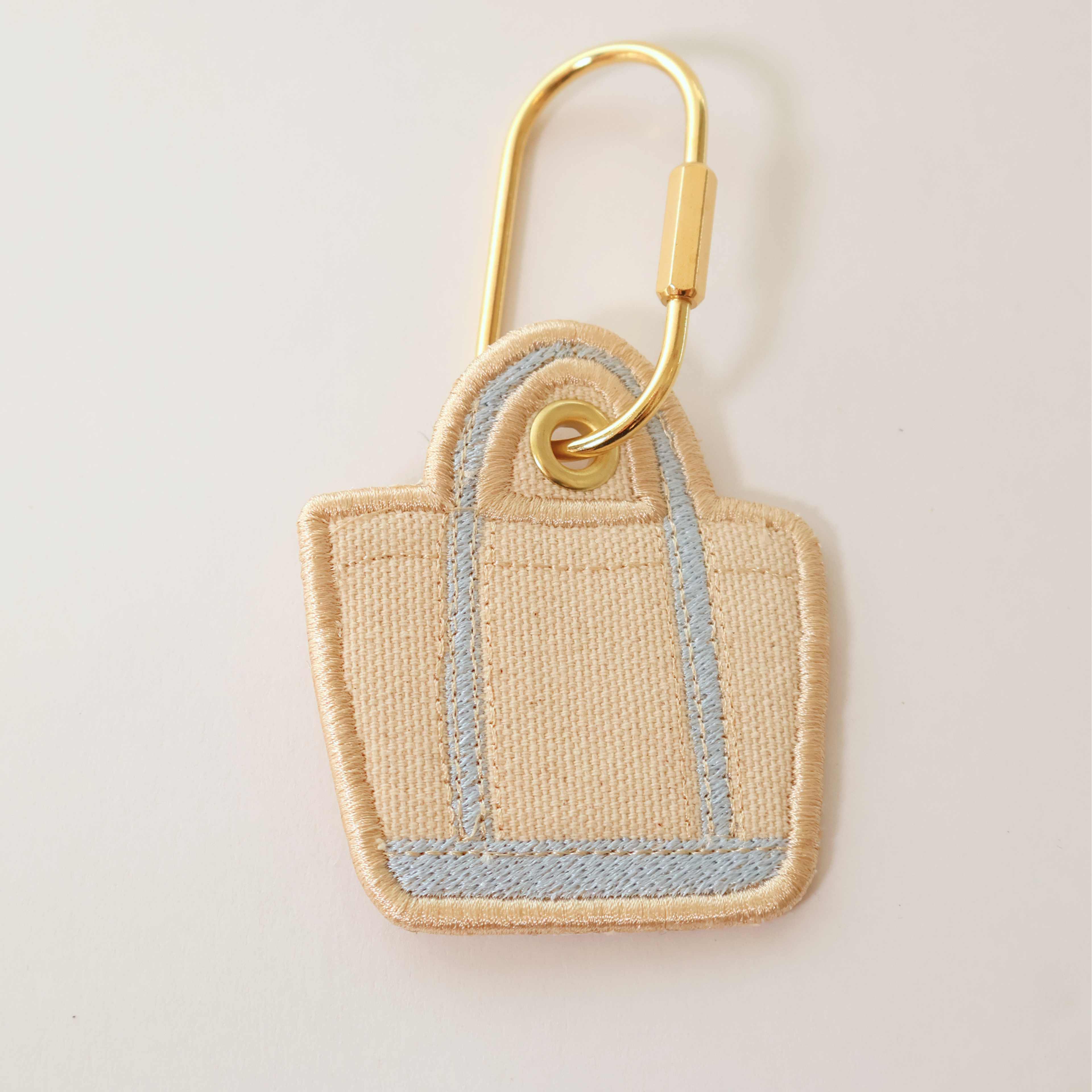Light blue bag shaped bag charm on a white background