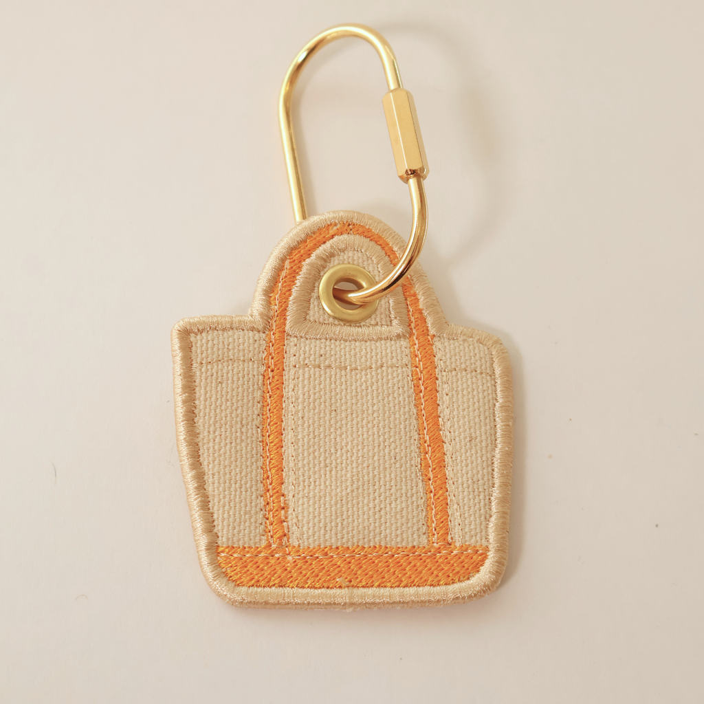 orange bag shaped bag charm on a white background