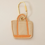 orange bag shaped bag charm on a white background