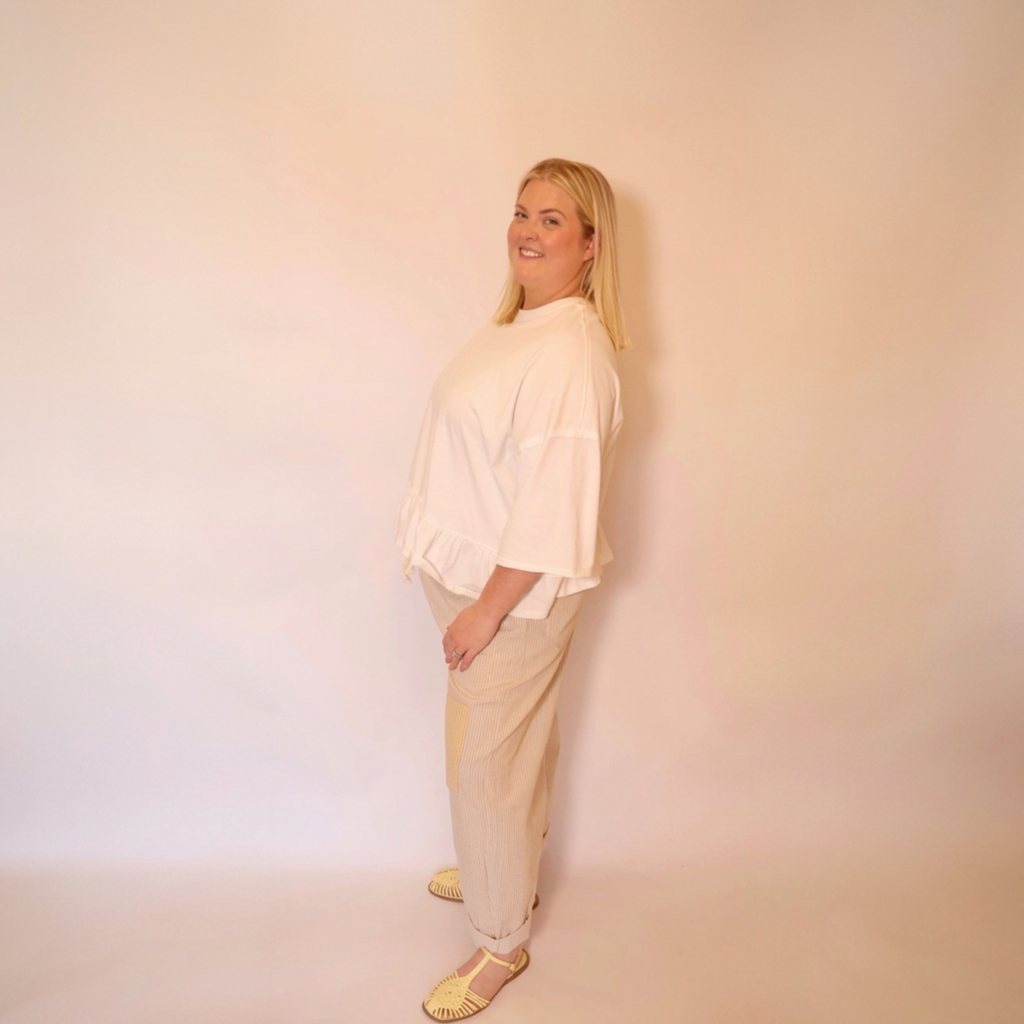 Woman facing left wearing the white willa tee and the hollis pants