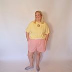 Woman wearing an embroidered T-shirt and the Tansy pink gingham cotton shorts facing forward