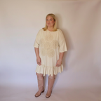 Woman facing forward wearing the cream laurel dress and tall pink boots.