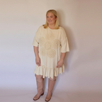 Woman facing forward wearing the cream laurel dress and tall pink boots.