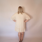 Woman facing backwards wearing the cream laurel dress and tall pink boots.