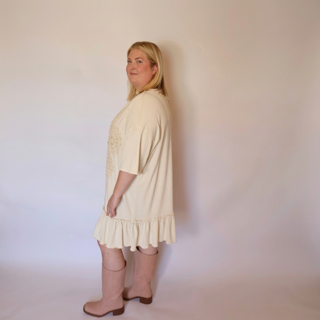 Woman facing left wearing the cream laurel dress and tall pink boots.