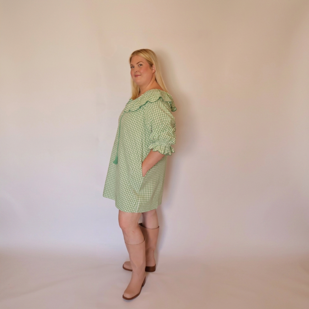 Woman facing left wearing the Green Gingham Louisa Dress and pink boots.